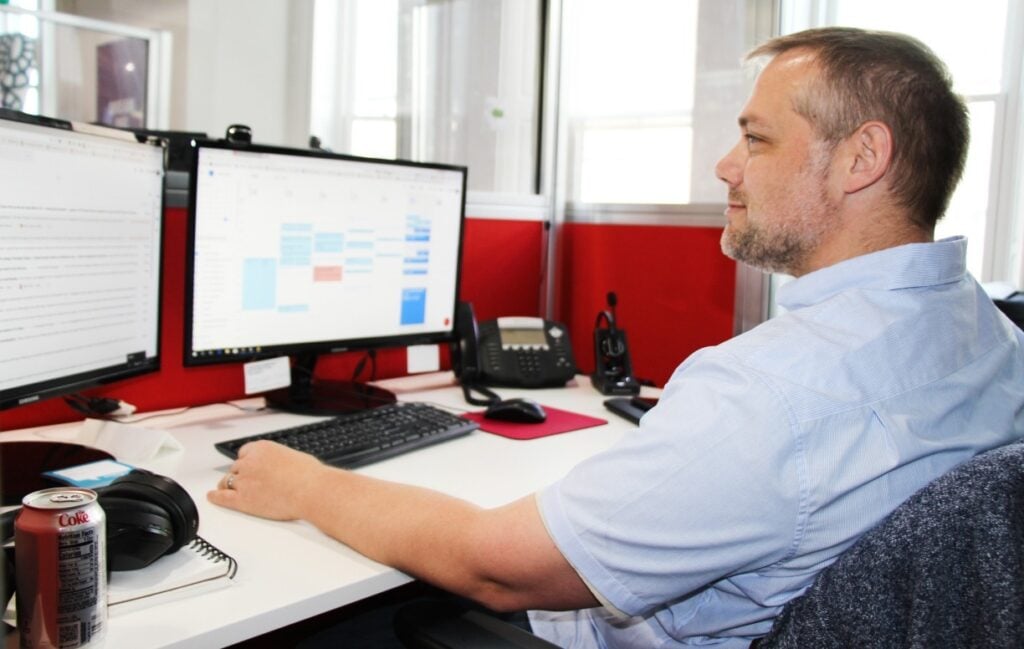 Homme à son bureau avec deux écrans.